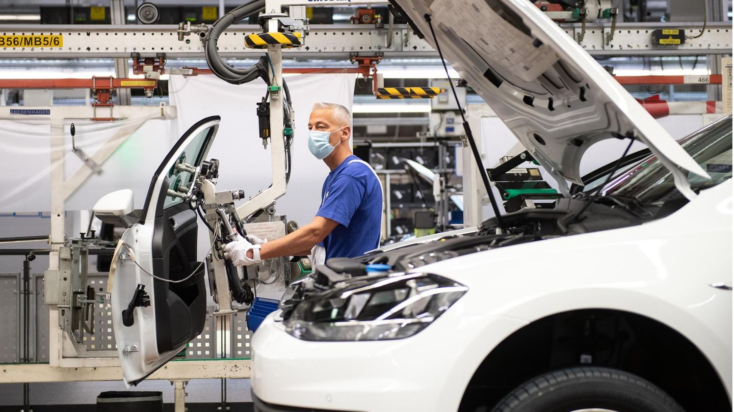 dpatopbilder - 27.04.2020, Niedersachsen, Wolfsburg: Ein Mitarbeiter steht mit einem Mund- und Nasenschutz an einem Fahrzeug und einer Tür in der Produktion. Volkswagen fährt nach dem Corona-Lockdown die wichtigsten Werke wieder schrittweise hoch. Foto:... Bislang produzieren die Fabriken in Deutschland trotz Corona
