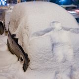 Der Abdruck eines Menschen auf der schneebedeckten Front eines Autos in Leipzig