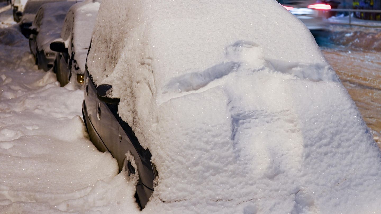 Der Abdruck eines Menschen auf der schneebedeckten Front eines Autos in Leipzig