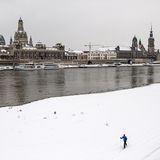 Vor der Silhouette Dresdens: Auf Skiern bewegt sich diese Person am verschneiten Elbufer entlang.