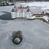 Der See um das Schloss Glücksburg in Schleswig-Holstein ist zugefroren, das Gebäude und die Landschaft drumherum sind mit Schnee überzogen.