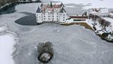 Der See um das Schloss Glücksburg in Schleswig-Holstein ist zugefroren, das Gebäude und die Landschaft drumherum sind mit Schnee überzogen.