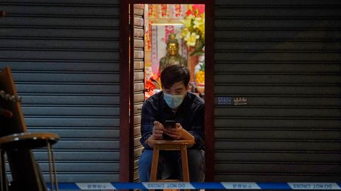 Ein Mann benutzt sein Smartphone im Eingang eines Geschäftes.