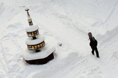 Ein Passant geht mit einem Snowboard über den Marktplatz von Wernigerode mit dem tiefverschneiten Marktbrunnen in Sachsen-Anhalt.