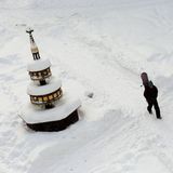 Ein Passant geht mit einem Snowboard über den Marktplatz von Wernigerode mit dem tiefverschneiten Marktbrunnen in Sachsen-Anhalt.