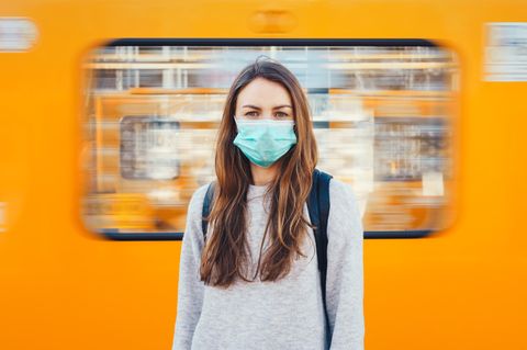 Coronavirus: Eine Frau mit Maske steht vor einer U-Bahn