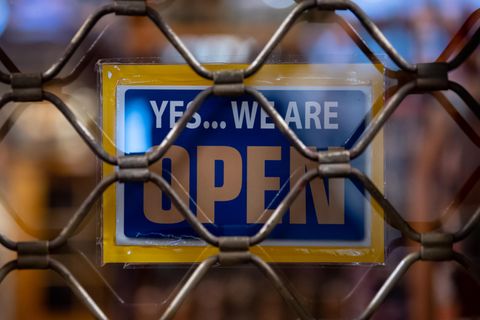 Ein Schild mit der Aufschrift «Yes...we are Open» ist kurz nach Ladenschluss an einem Geschäft zu sehen
