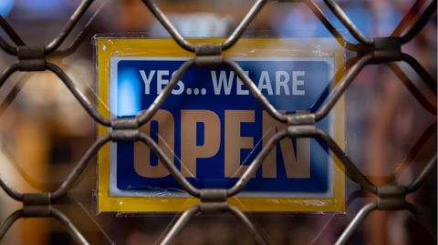 Ein Schild mit der Aufschrift «Yes...we are Open» ist kurz nach Ladenschluss an einem Geschäft zu sehen