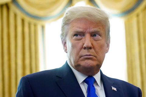 Donald Trump steht im Anzug im Oval Office vor einem Fenster mit goldenen Vorhängen