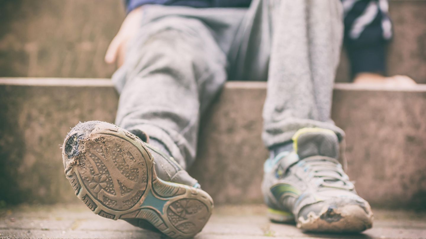 Kind mit kaputten Schuhen