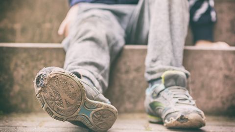 Kind mit kaputten Schuhen