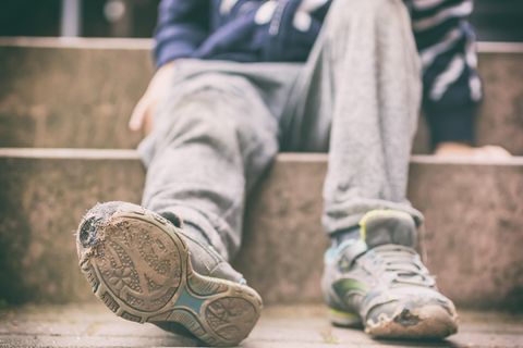 Kind mit kaputten Schuhen