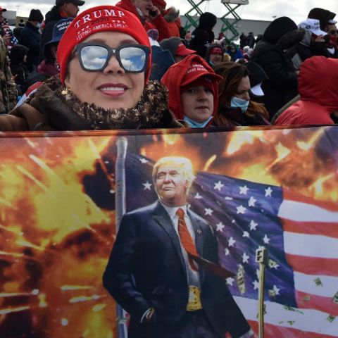 Eine Frau hält bei einer Wahlkampfveranstaltung eine Fahne auf der Ex-US-Präsident Trump zu sehen ist