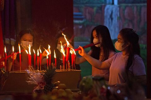 Vier Jugendliche entzünden Kerzen in einem chinesischen Tempel.