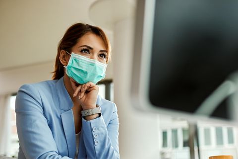 Coronavirus Ansteckungsrisiko: Eine Frau mit Maske steht in einem Büro