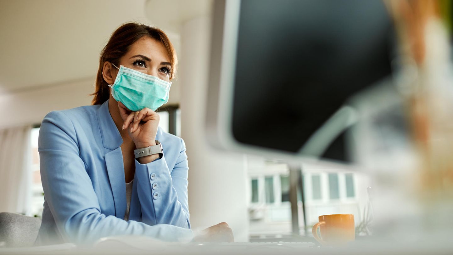 Coronavirus Ansteckungsrisiko: Eine Frau mit Maske steht in einem Büro