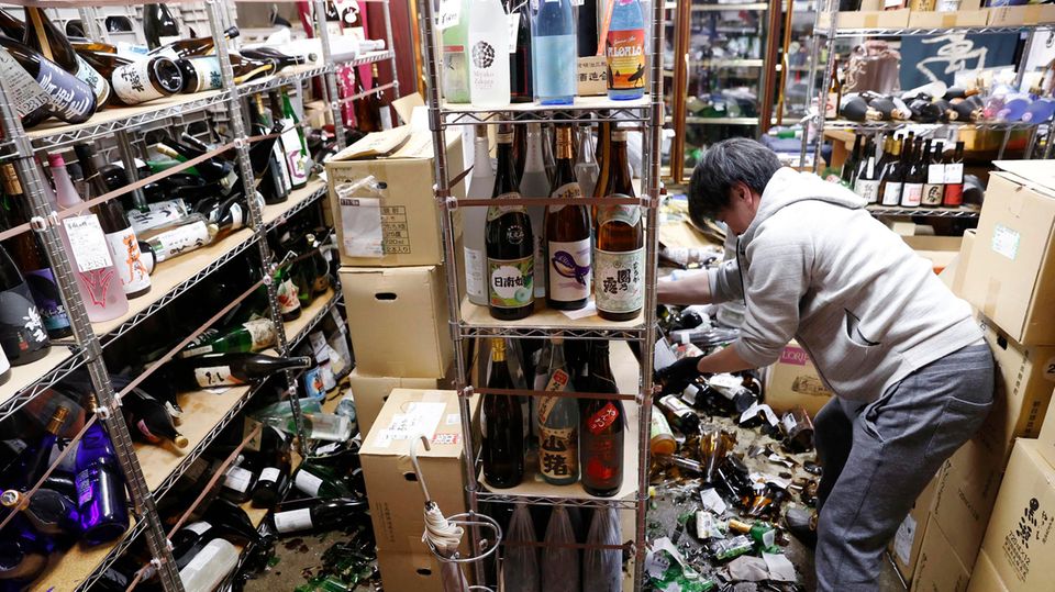 Fukushima Erdbeben Japan Der Inhaber eines Spirituosengeschäfts räumt nach einem starken Erdbeben in seinem Geschäft auf. Am Boden zerstörte Flasche