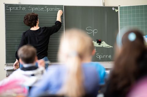 Lehrerin schreibt an einer Tafel.