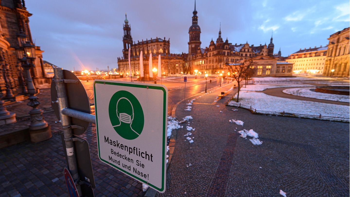 Ein Hinweisschild auf die Maskenpflicht hängt auf dem Theaterplatz in Dresden