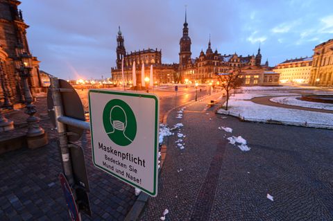 Ein Hinweisschild auf die Maskenpflicht hängt auf dem Theaterplatz in Dresden