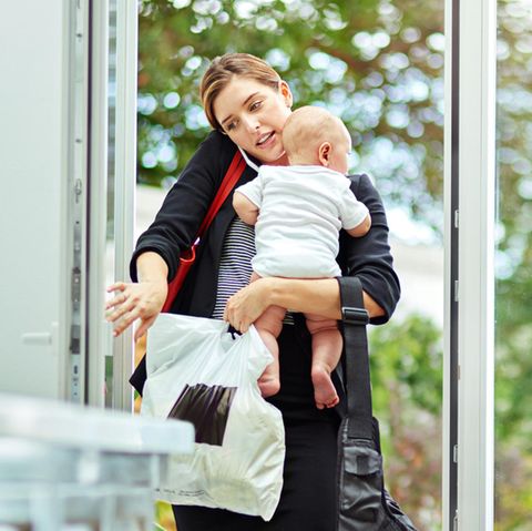 Frau in Business-Kleidung mit Baby auf dem Arm