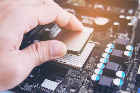 Intel vs. AMD: Eine CPU wird in den Sockel gelegt.