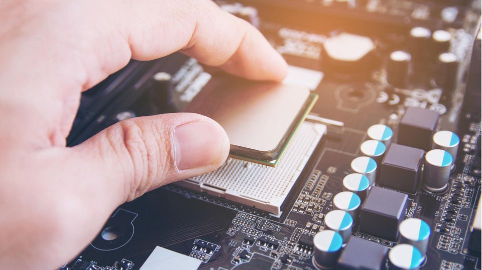 Intel vs. AMD: Eine CPU wird in den Sockel gelegt.