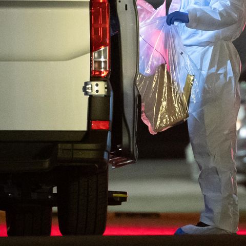 Ein Kriminaltechniker bringt einen Plastikbeutel zum Wagen