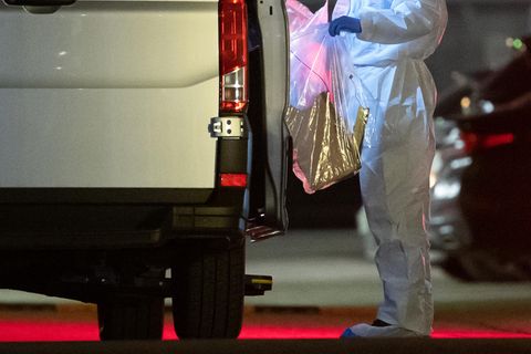 Ein Kriminaltechniker bringt einen Plastikbeutel zum Wagen
