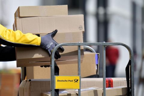 Postgesetz - Ein Paketbote lädt Pakete von einem Wagen