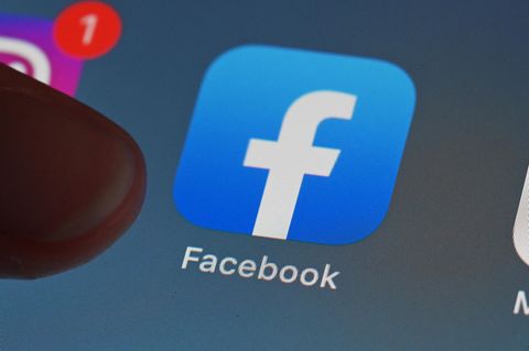 Eine Person zeigt auf einem Tablet auf die Facebook App.