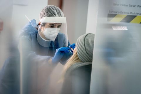 Eine Mitarbeiterin einer Corona-Schnellteststation nimmt einen Mund- und Nasenabstrich für einen Corona-Schnelltest.