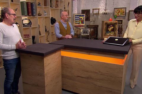 Gerhard Degenkolb, Moderator Horst Lichter und Expertin Heide Rezepa-Zabel stehen im "Bares für Rares"-Studio in Pulheim
