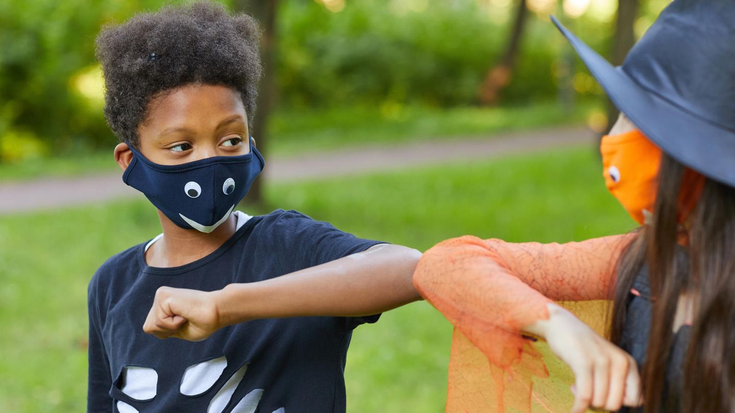 Zwei Kinder mit Masken grüßen sich mit den Ellbogen