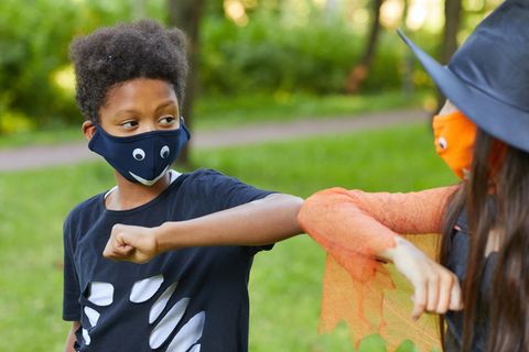 Zwei Kinder mit Masken grüßen sich mit den Ellbogen