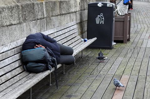 Ein Obdachloser schläft auf einer Bank