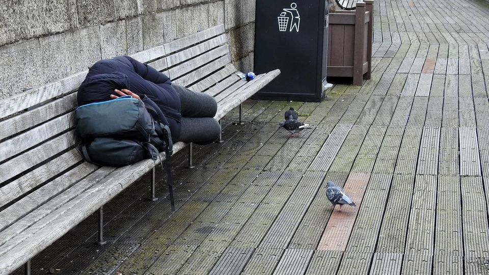 Ein Obdachloser schläft auf einer Bank