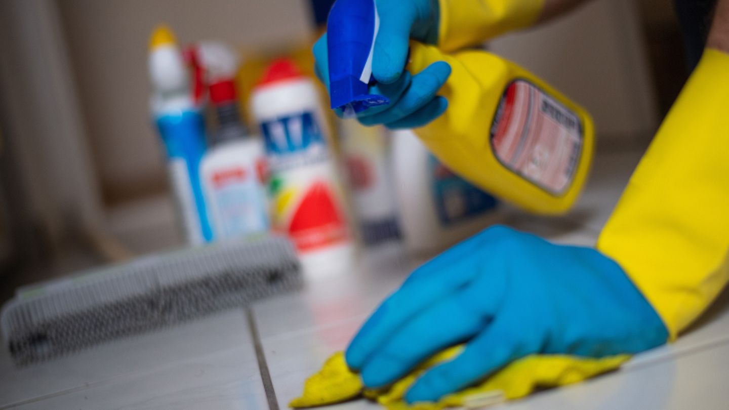 Ein Mann putzt in Gummihandschuhen Fliesenboden in einer Wohnung