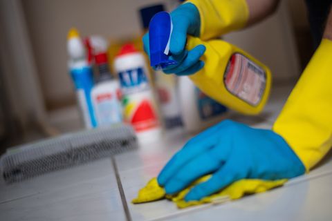 Ein Mann putzt in Gummihandschuhen Fliesenboden in einer Wohnung