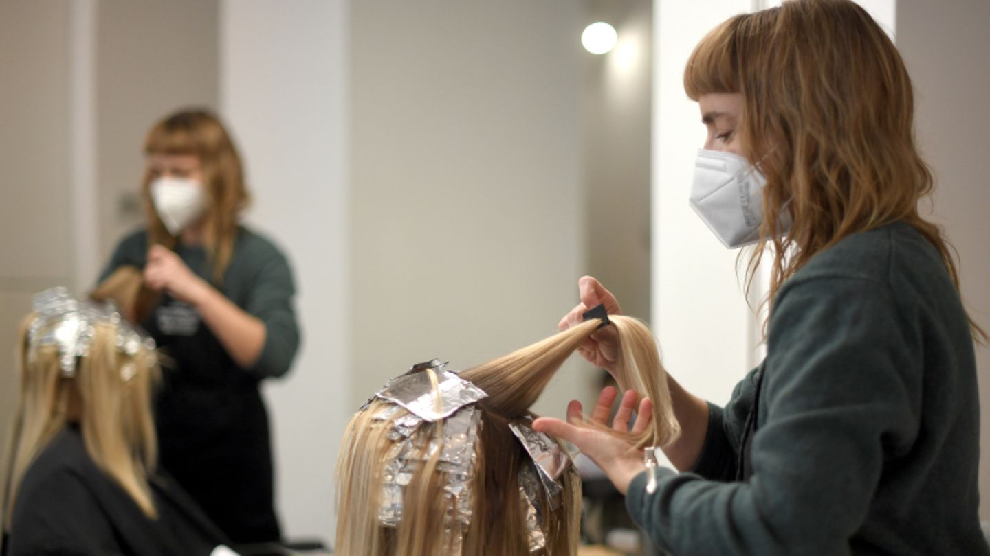Friseurin beim Haarefärben einer Kundin mit Mundschutz