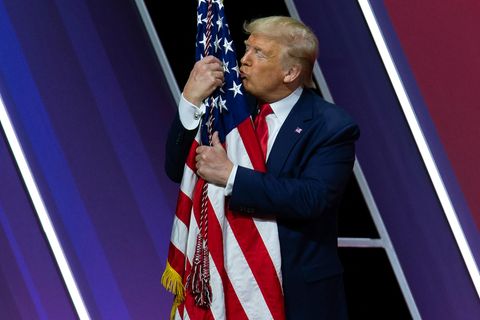 Donald Trump küsst und umarmt eine amerikanische Flagge
