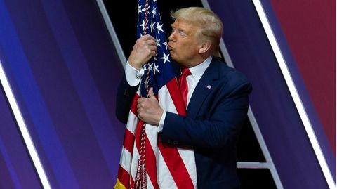 Donald Trump küsst und umarmt eine amerikanische Flagge