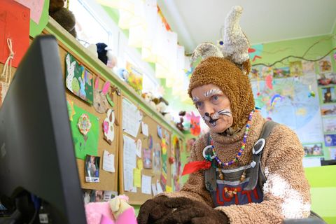 Eine Frau in einem Osterhasen-Kostüm und mit aufgeschminkten Hasenzähnen tippt in einem Büro am Computer