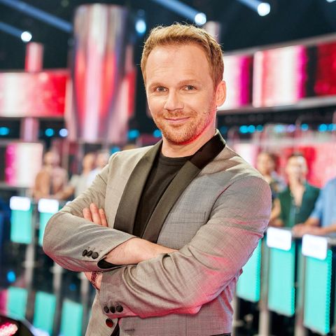 Ralf Schmitz steht im Take me out Studio in Köln und schaut in die Kamera