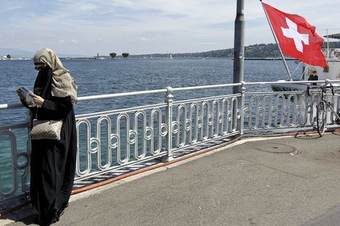 Eine Frau mit Niqap steht am Genfer See und liest in einem Stadtplan.