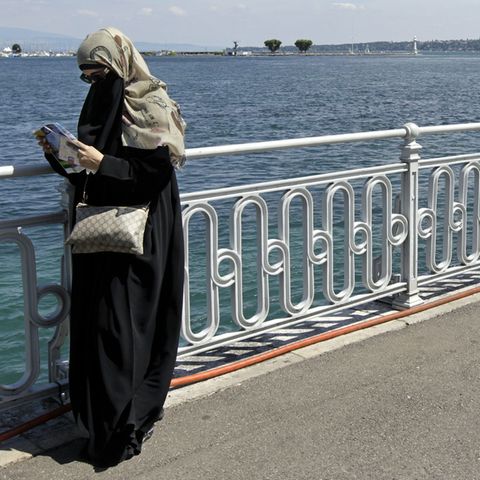 Eine Frau mit Niqap steht am Genfer See und liest in einem Stadtplan.