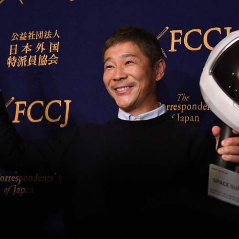 Der Milliardär Yusaku Maezawa vor einer schwarzen Wand, er hält eine Modellrakete und einen Raumfahrthelm