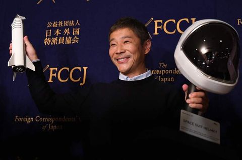 Der Milliardär Yusaku Maezawa vor einer schwarzen Wand, er hält eine Modellrakete und einen Raumfahrthelm
