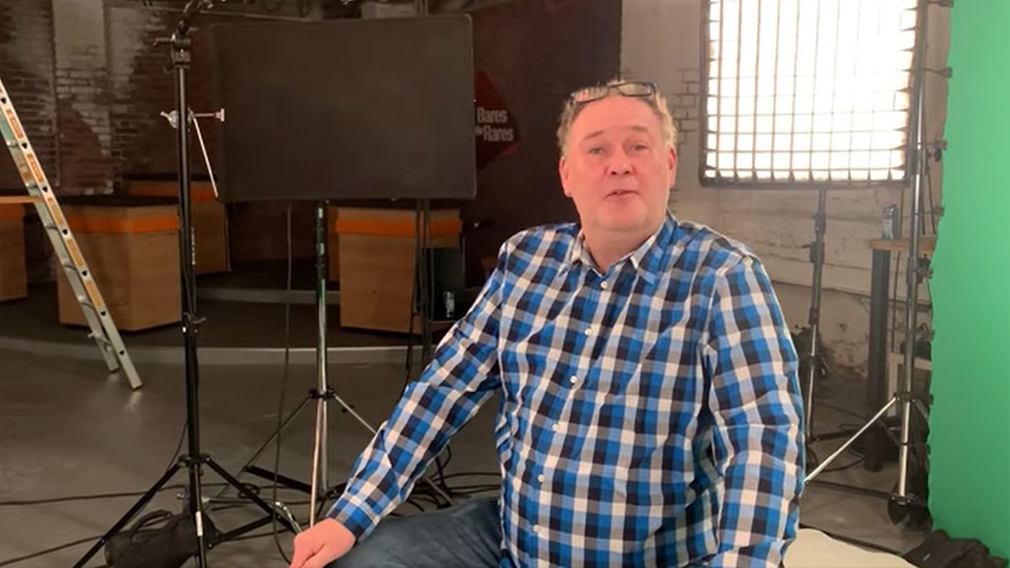 Walter Lehnertz sitzt im Studio von Bares für Rares in Pulheim in Köln. Im Hintergrund ist der Händlerraum zu sehen.
