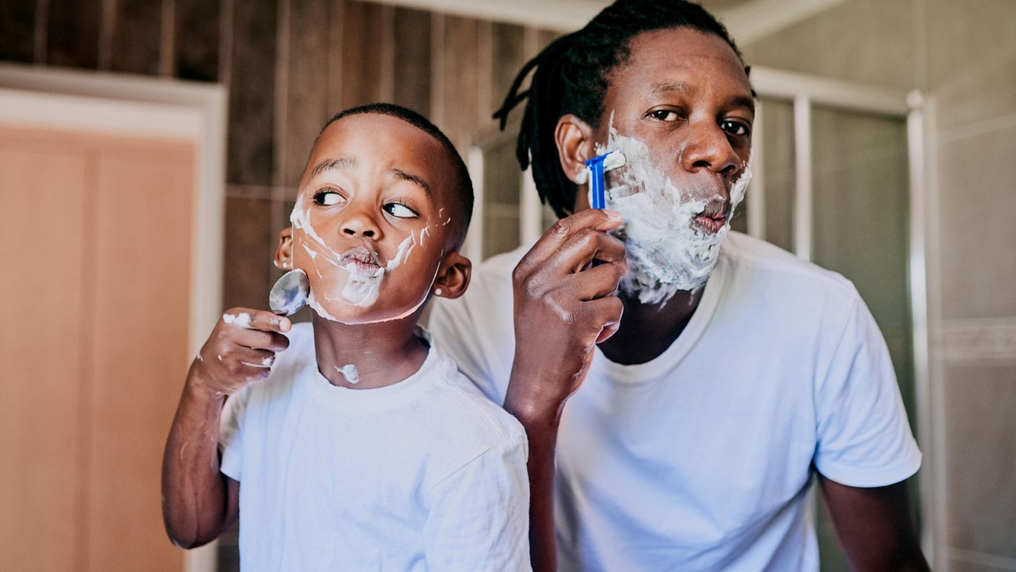 Bart rasieren: Ein Vater rasiert sich mit seinem Sohn vor dem Spiegel.